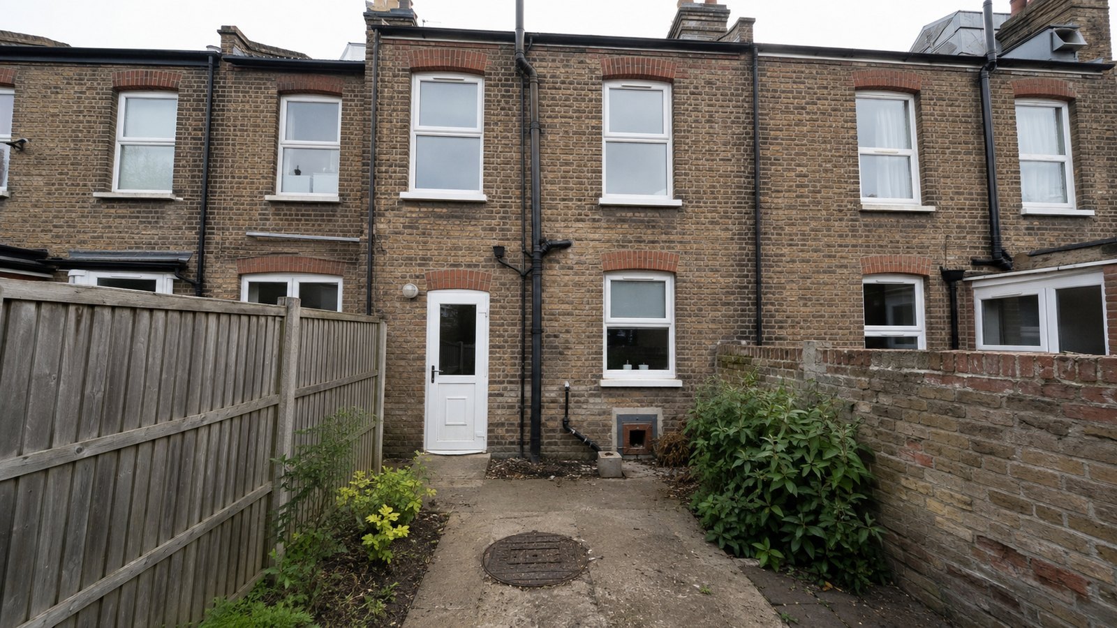 Rear of an older UK terraced house with soil stack, gullies and inspection chamber